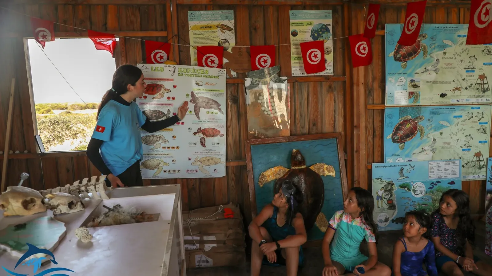 Une photo d'enfants assis dans une cabane de sensibilisation d'une organisation pour apprendre à connaître les posidonies et l'importance de la préservation des tortues sur l'île de Kuriat.