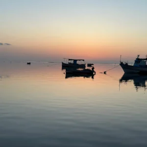 A picture of 2 boats mooring in the sea of Kerkennah island during the sunset
