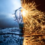 Light bulb split between water and fire, symbolizing the energy-water nexus with splashing water on one side and bright sparks on the other.